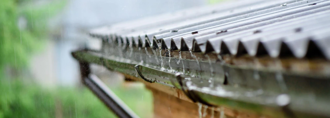 Pluie tombant sur un toit en métal avec gouttières.