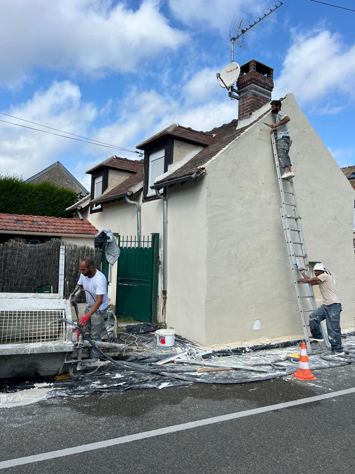 Travailleurs rénovant la façade d'une maison.