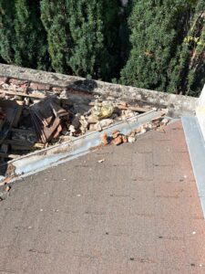 Toit endommagé avec débris près des arbres verts.
