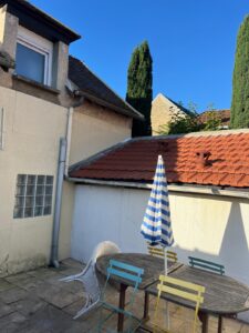 Terrasse ensoleillée avec meubles colorés et parasol.