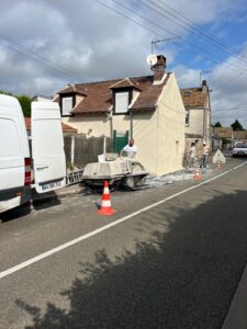 Travaux de façade maison avec camionnettes stationnées.
