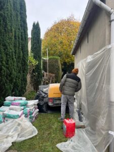 Homme travaillant dans un jardin avec matériaux de construction.