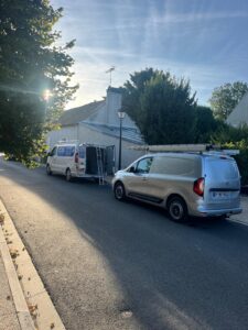 Vans garés devant une maison ensoleillée.