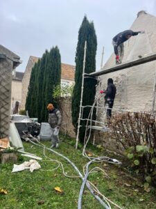 Travailleurs réparent façade maison sur échafaudage.