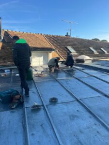 Travailleurs sur un toit en métal sous le soleil.